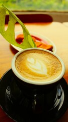 Hot Coffee Latte Art in a Black Cup on Wooden Table