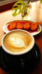Hot Coffee Latte Art in a Black Cup on Wooden Table