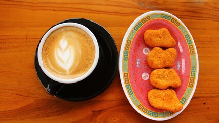 hot coffee latte art and nuggets served on a wooden table
