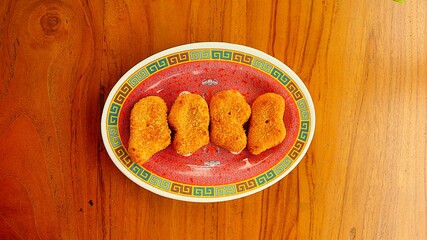 Golden Crispy Chicken Nuggets on a Plate on Wooden Table