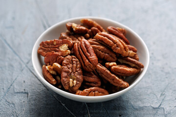 Pecan nuts in a white bowl on a rustic table