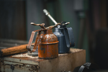 Two manual oilers on a bench by the mill in a metal workshop.