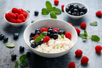 Bowl of cottage cheese, curd cheese with blueberry and raspberry. High protein healthy breakfast or lunch