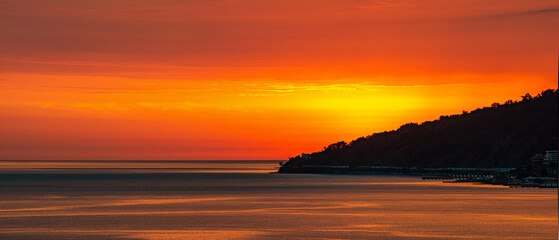 Fototapeta premium In the distance, there is a large body of water with a city skyline on sunset