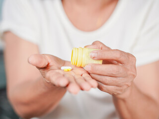 Lifestyle Health Care Concept. Elderly woman holding medicine in his hand, Sick person taking medicine to take care of health. Young Asian woman taking medicine to relieve her illness.