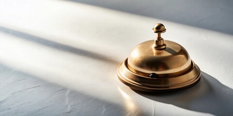 A gleaming gold service bell sits on a softly textured surface, bathed in the warm glow of sunlight, a symbol of attentive assistance and immediate response