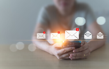 A woman sits and checks her email inbox to open it, whether it's for business or spam, using her mobile phone at home. convenient life, borderless communication with modern technology Background blur