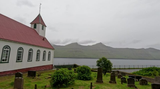 Kunoy, Faroe Islands : July 19, 2024 Rear view of the historic Church of Kunoy building exterior and cemetery grounds. The church faces the North Atlantic Ocean and dates back to 1867.