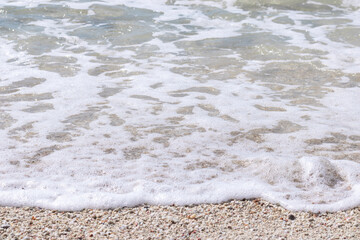 Close up view of a calm wave washing up on a sandy shore 