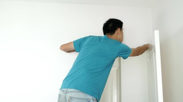 A person in a blue shirt demonstrates how to install a door. This image captures the process and tools involved, making it a helpful visual guide for DIY enthusiasts looking to enhance their home impr