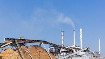 Biomass power plant with wood fuel storage system amidst blue sky, Renewable energy, Green energy,...