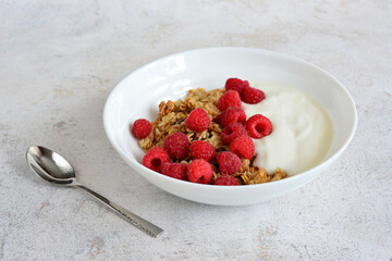 Granola with Yogurt and Raspberries in a white bowl healthy breakfast