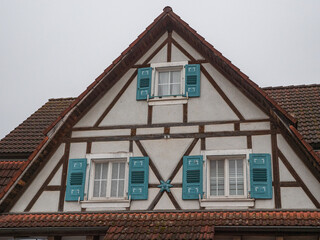 Aussenansicht eines Giebels mit türkisfarbenen Fensterladen an einem Fachwerkhaus