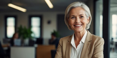 A happy and successful older female entrepreneur in an office environment, holding a tablet and looking away with a confident smile