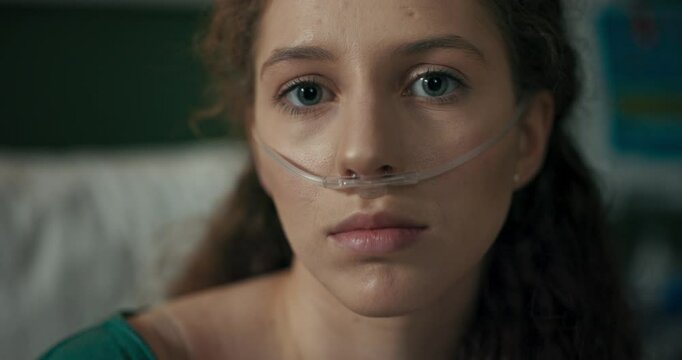 In the hospital room, the young girl laughs heartily despite her oxygen tube.