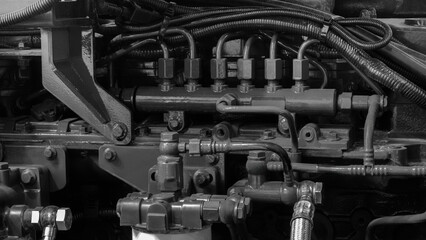 A close up of a large engine with many pipes and valves. The engine is black and white