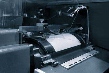 A printer machine with a paper roll in it. The machine is black and silver