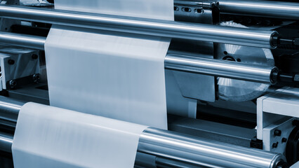 Automatic polyethylene plastic bag production machine with lighting effect. Close-up of the roller of the plastic bag production machine in the light blue scene. product packaging concept