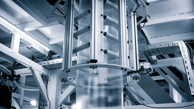 Automatic polyethylene plastic bag production machine with lighting effect. Close-up of the roller of the plastic bag production machine in the light blue scene. product packaging concept