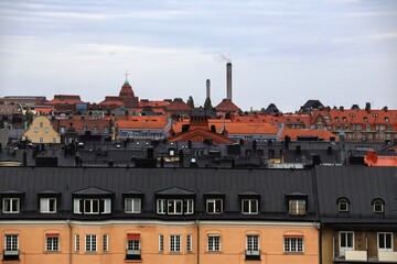 Rooftop cityscape with chimneys in stockholm, showcasing red-tiled roofs and urban density