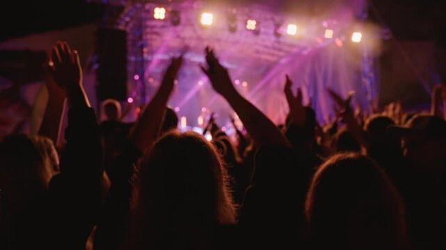 Vibrant live concert scene with band performing on stage under bright spotlights. People enjoying live music performance at an outdoor concert
