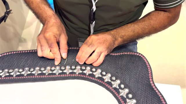 Men embellishing horse breastplate.Focus on embellishing horse breastplate with intricate design symbolizes skilled artisanship passed down through generations. Handmade decorative technique