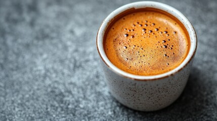 Close-up of a freshly brewed espresso in a speckled cup on a textured gray surface