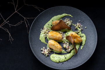 Savor gourmet potato gnocchi with creamy avocado sauce and crispy chips for texture