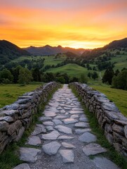 A serene stone pathway leads through lush hills, framed by a vibrant sunset sky, creating a peaceful and picturesque landscape.