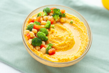 Delicious hummus topped with chickpeas, broccoli, and bell peppers. A healthy and flavorful vegetarian snack or meal.