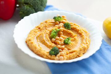 Delicious carrot hummus topped with chickpeas and broccoli florets. A healthy and vibrant appetizer or snack.