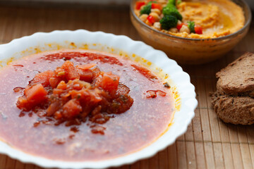 Hearty tomato soup served with hummus and bread. A simple yet satisfying meal.