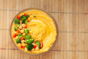 Delicious hummus topped with chickpeas, broccoli, and bell peppers. A healthy and flavorful vegetarian meal.