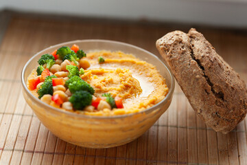Delicious hummus with chickpeas, broccoli, and red peppers, served with crusty bread.