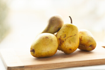 Ripe yellow pears on a wooden cutting board, ready for use in a recipe or dessert. A rustic and natural still life.
