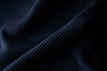 Close-up of textured dark fabric. Deep navy ribbed material, showing folds and wrinkles. Perfect for fashion, design, and textile projects.