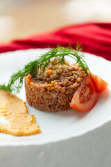 Buckwheat dish with tomato and dill garnish, served with a side of creamy sauce. A delicious and healthy meal.