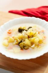 A bowl of hearty vegetable soup, featuring potatoes, broccoli, and carrots in a clear broth.