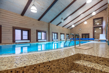 Private swimming pool decorated with beige mosaic tiles. The room is made of natural wood.
