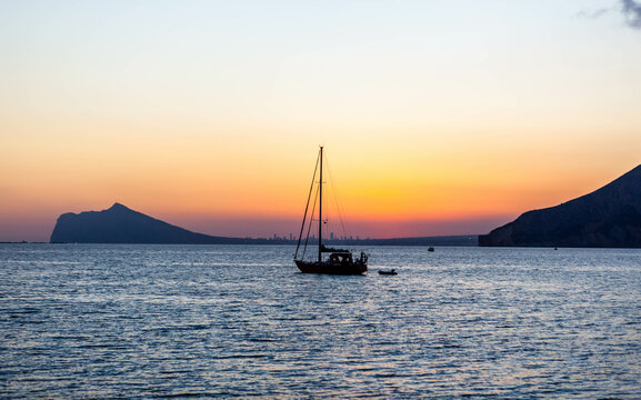 Sailboat view at sunset over Benidorm town in the province of Alicante, Valencian Community, Spain. Mediterranean sea coast in Costa Blanca region.