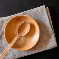 Wooden spoon and plate on a napkin stand on a black table