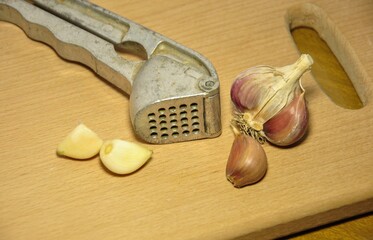 old garlic press and garlic bulbs on a wooden cutting board. selective focus