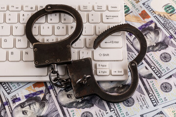 Steel handcuffs and computer keyboard on a background of 100 US dollar bills