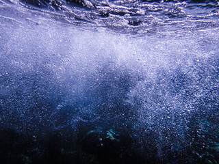 Dark blue ocean surface seen from underwater. Abstract waves underwater and rays of sunlight...