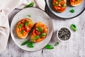 Appetizing bruschetta with tomatoes, garlic and basil on a plate on the table top view