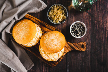 Hearty burgers with egg, tomato, cheese and garlic salad on a board on a table top view
