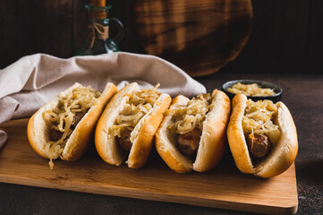 Homemade hot dogs with caramelized onions on a board on a table