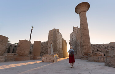 Happy woman traveler explores the ruins of the ancient Karnak temple in the heritage city of Luxor...