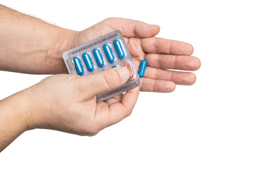 Male hand taking out blue medicine capsule from blister pack, antibiotic pills, or painkillers,...