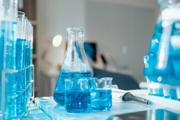 Laboratory glassware containing blue chemical liquid stands on table